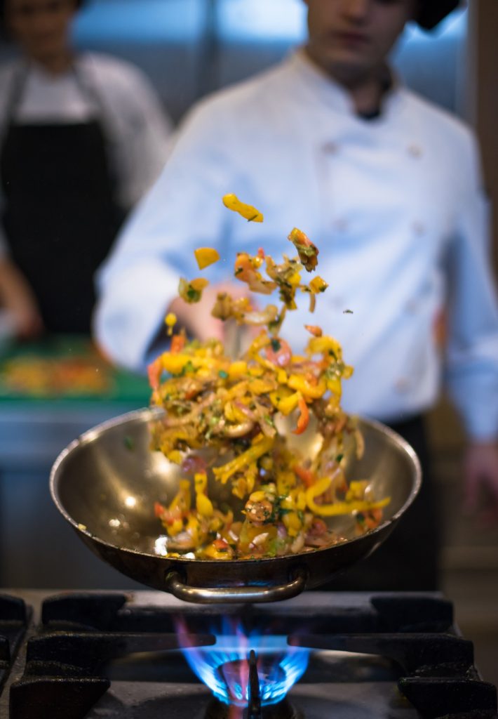 chef flipping vegetables in wok